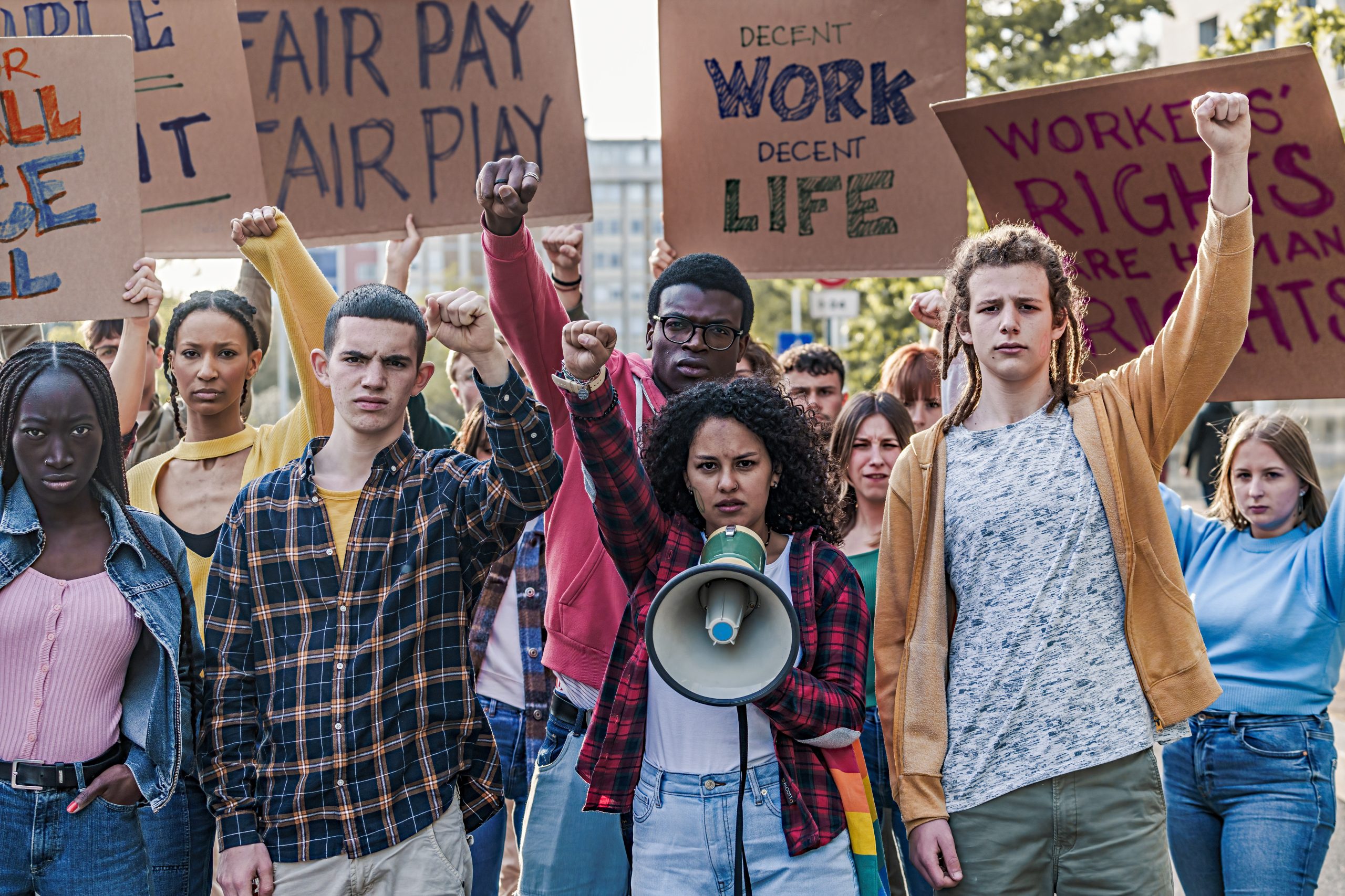 np_A group of multi-ethnic youth protesting for fair pay and work access, raising fists_432QeO_standard_photo